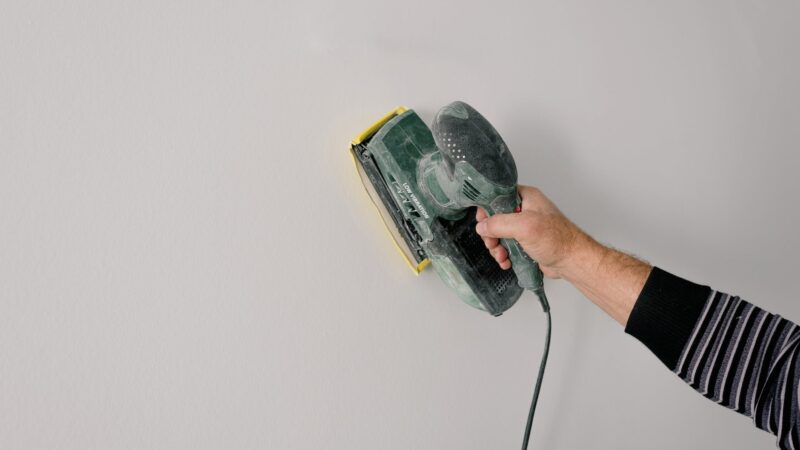 repairman polishing wall with construction tool